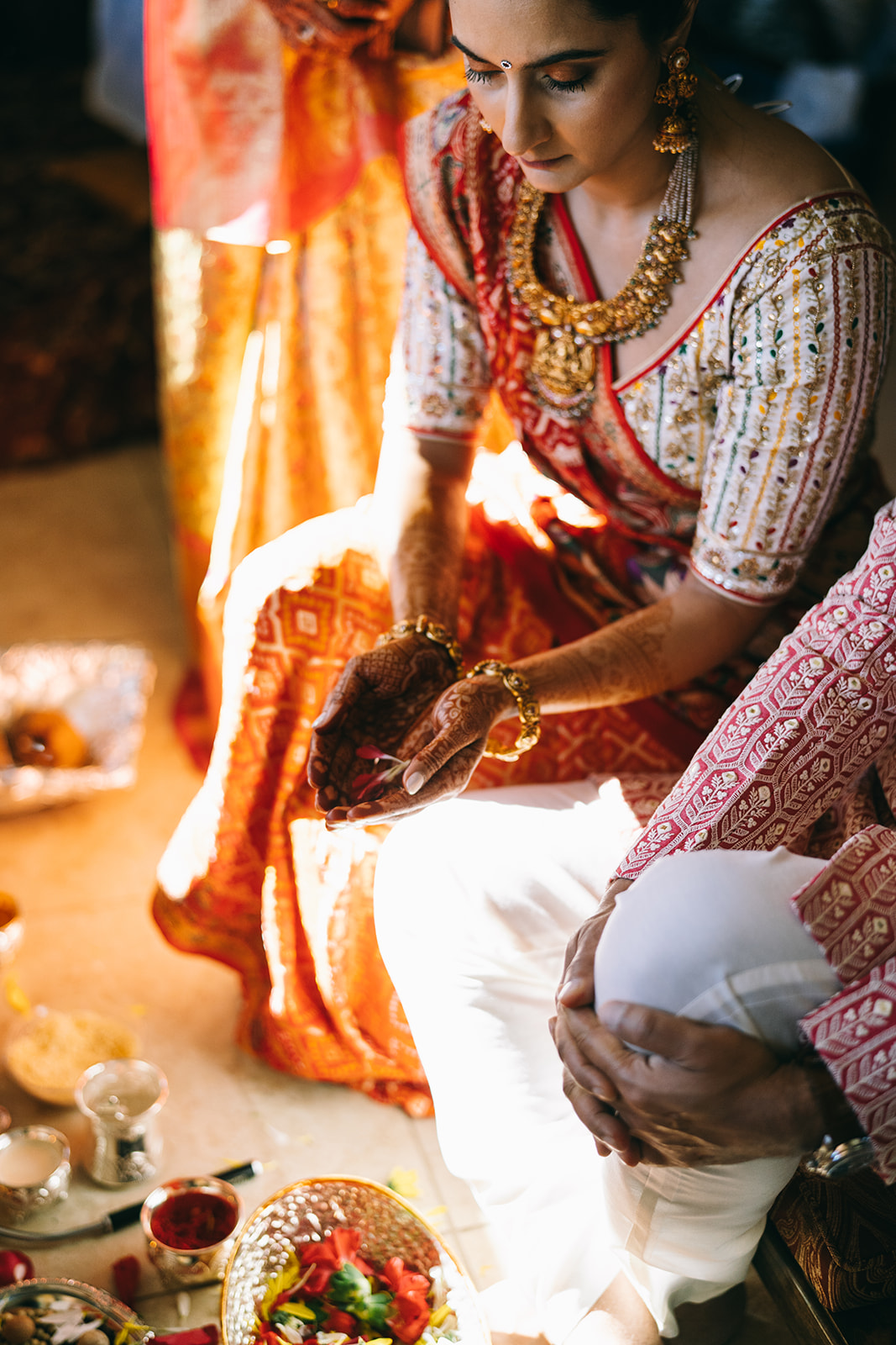 Indian woman in wedding saari holding flower petals in hands with henna
