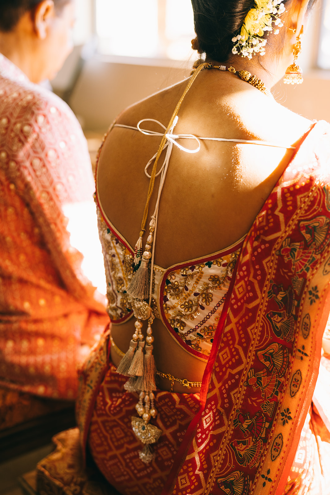 Back of Indian wedding dress with tassels and beads and the back of a saari
