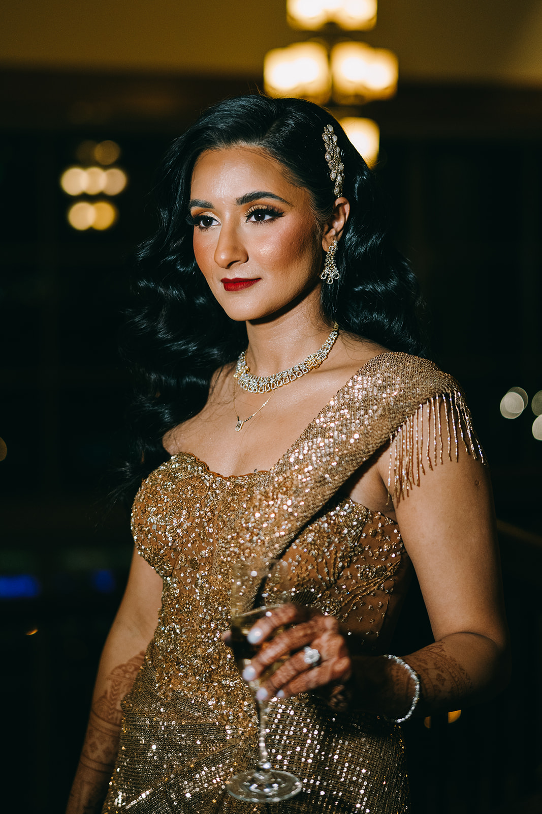Woman in golden sequined dress with her hair down looking away from camera