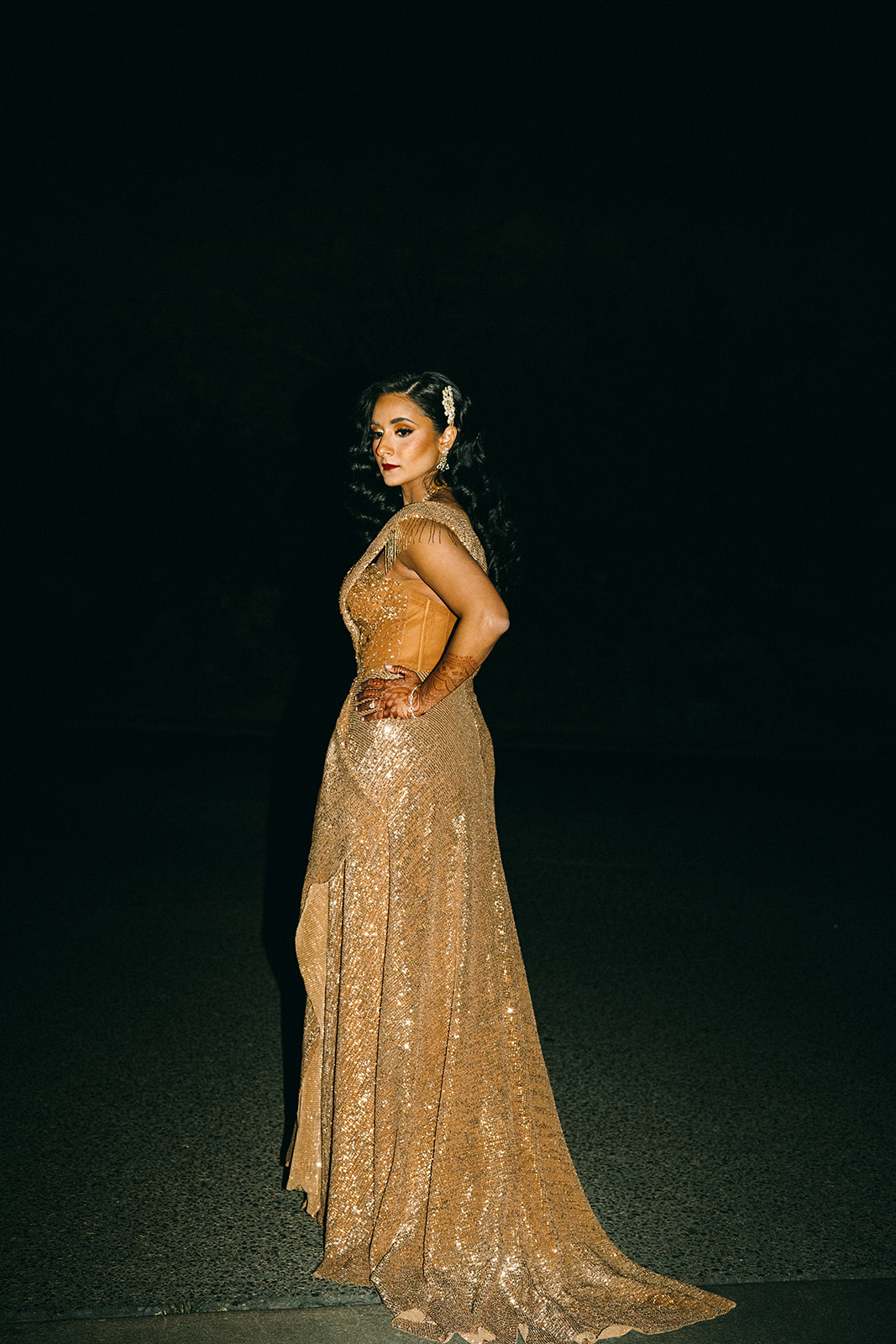 Woman in golden dress with her hand on her hip from far away