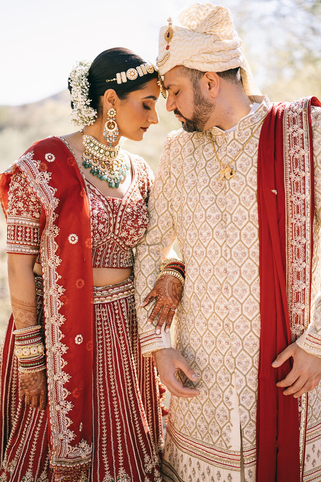 Indian bride and groom standing side by side touching foreheads and looking down