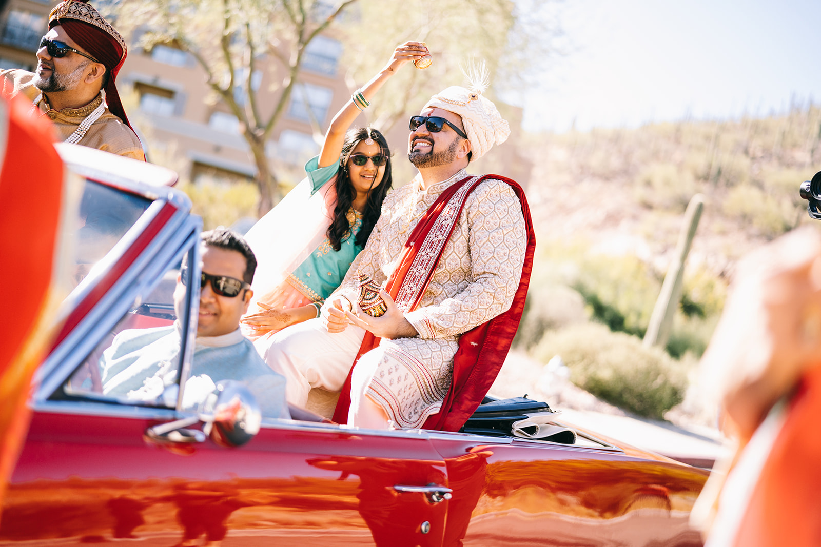 Man sitting on convertible next to a woman in teal dress 