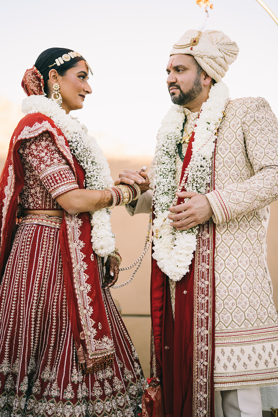 Indian bride and groom looking at each other and holding hands