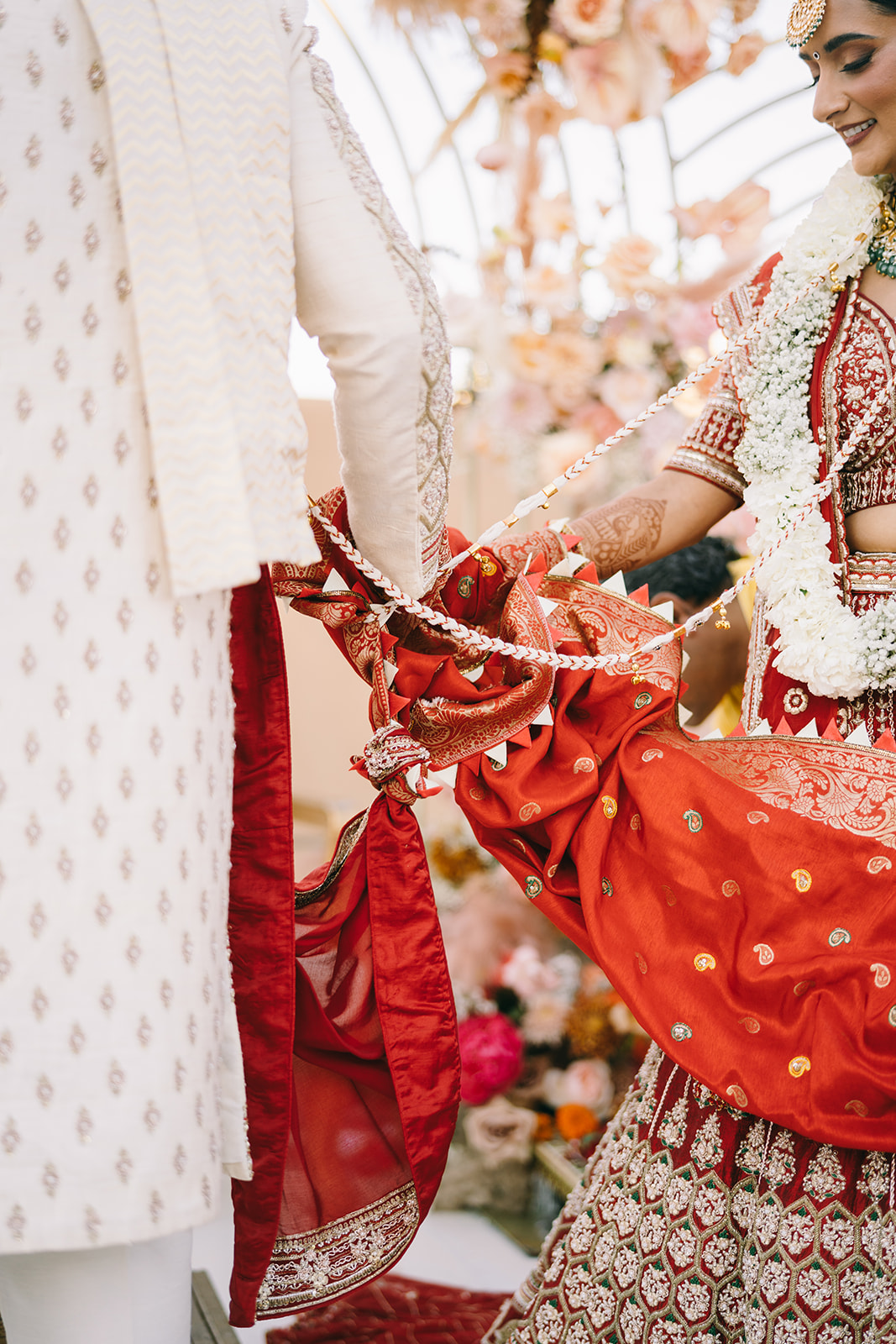 Indian groom and bride putting their hands together in a red fabric
