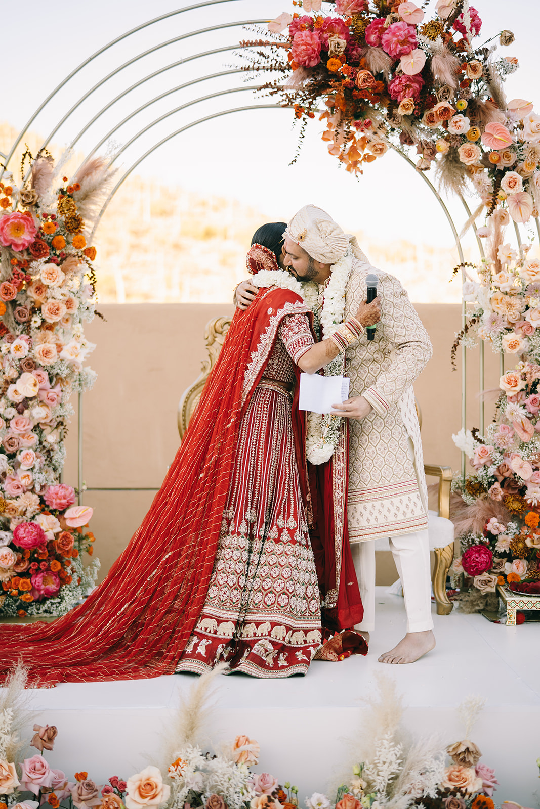 Indian bride and groom embracing underflower arch