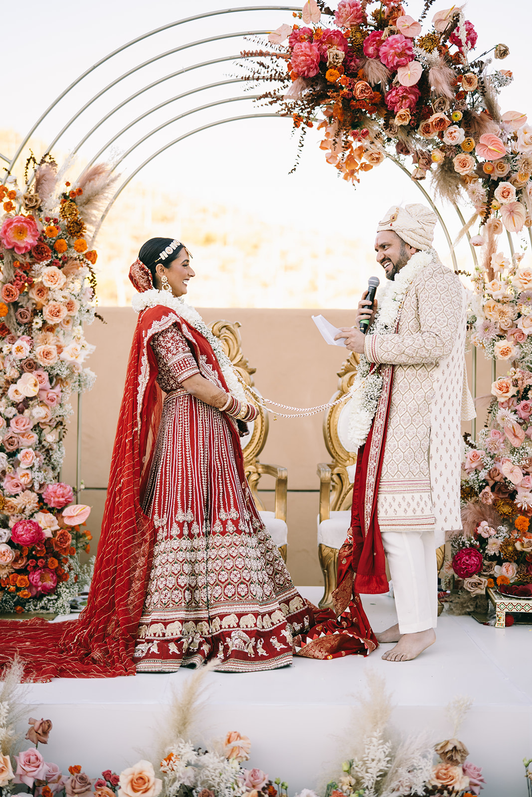 Groom holding microphone and looking at his bride who is laughing 