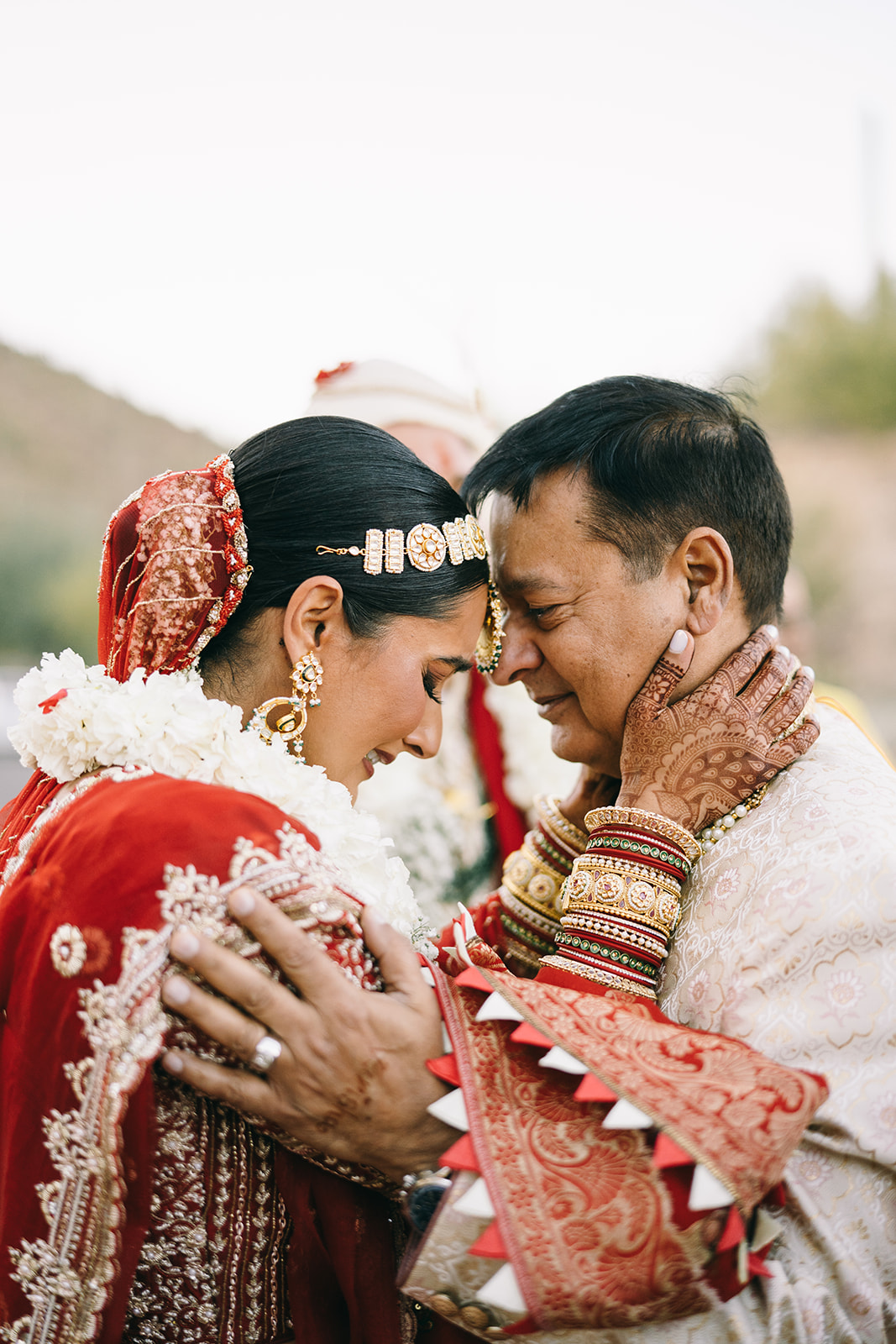 Indian bride touching foreheads with an older indian man touching her shoulders