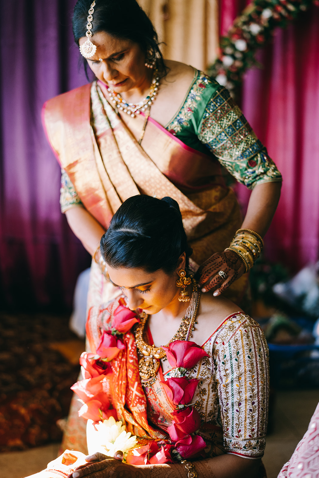 mother of the bride putting a necklaces of roses on daughter at Indian wedding