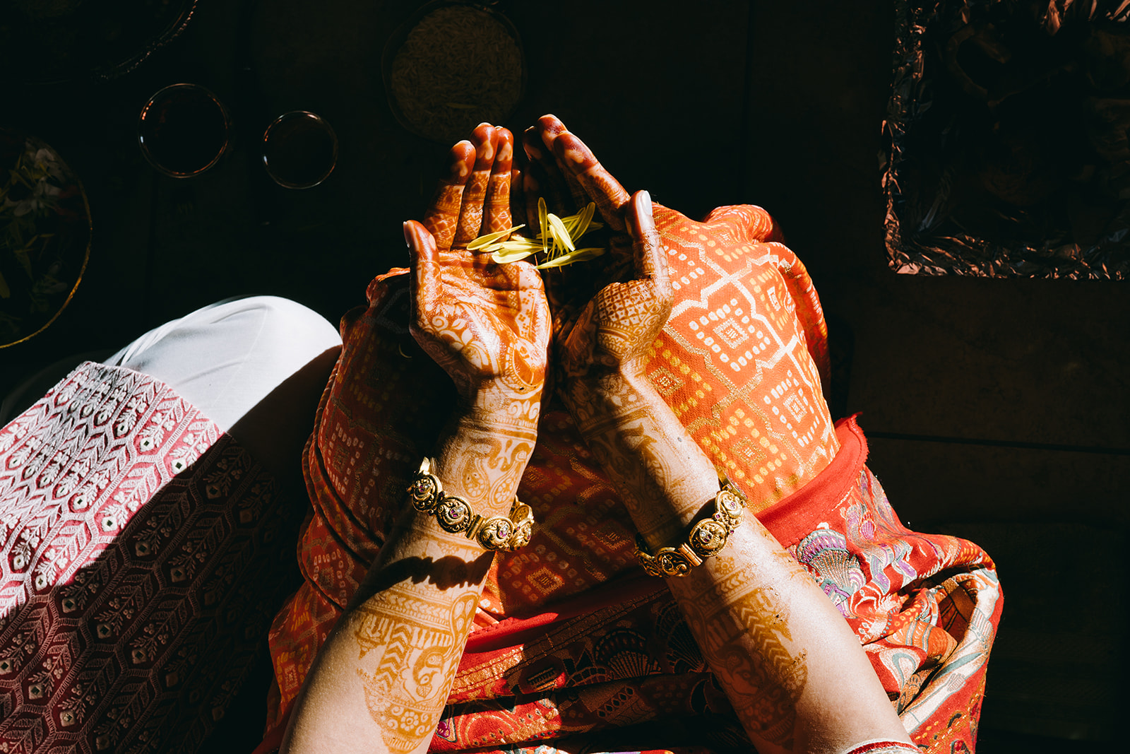 orange and gold saari underneath woman's outstretched arms with gold jewelry