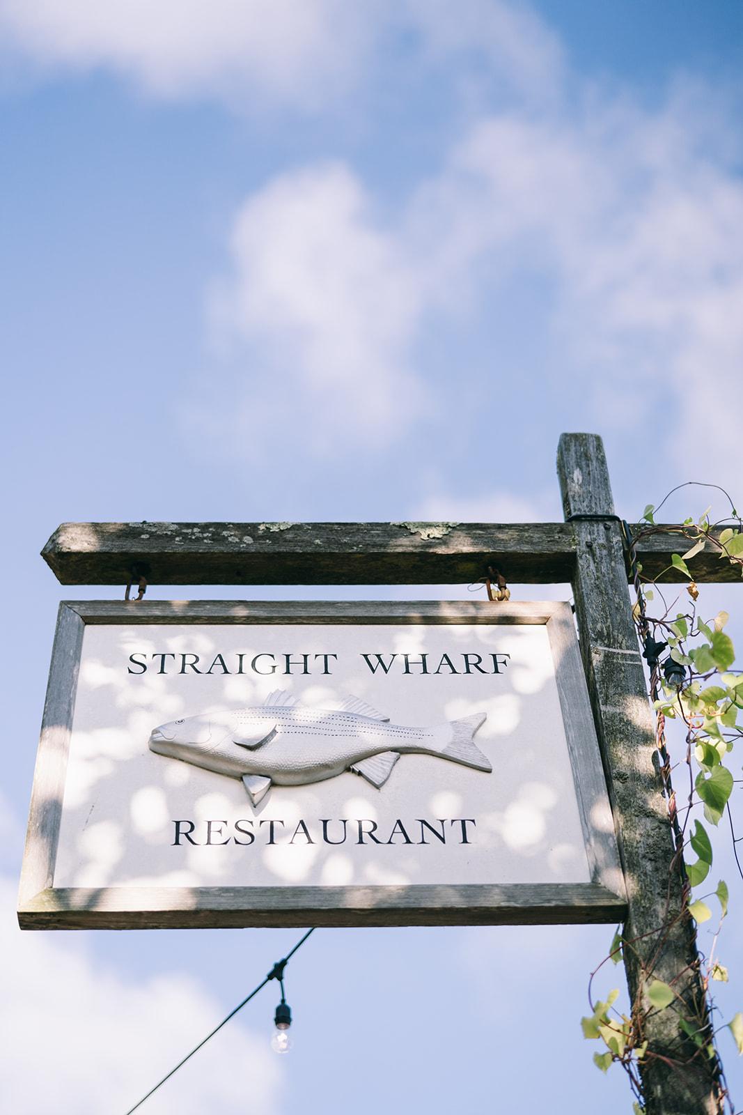 Sign against a blue sky with a few clouds that says 'Straight Whale Restaurant' in Nantucket