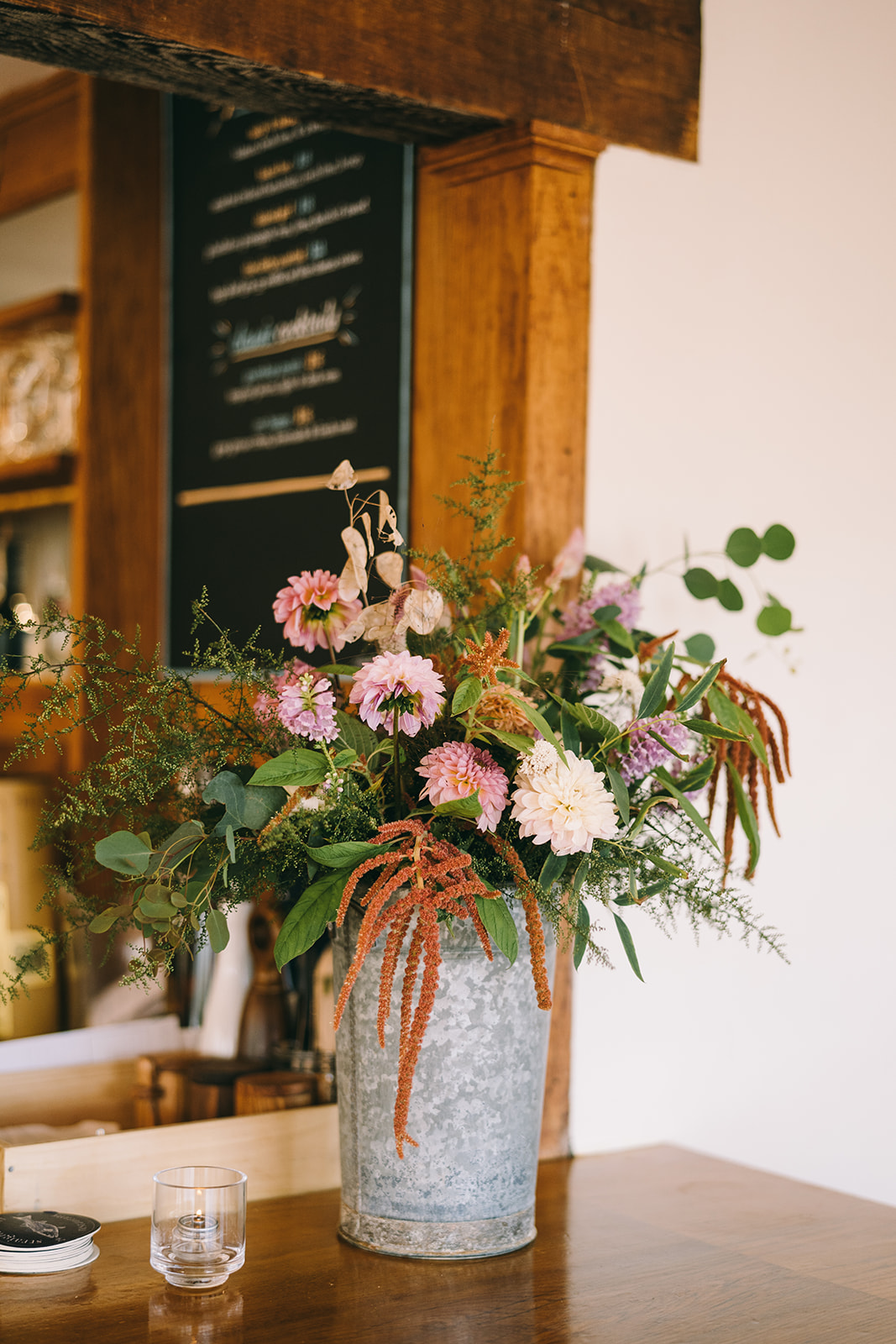 Flowers in a tin bucket on a table in a restaurant with white walls