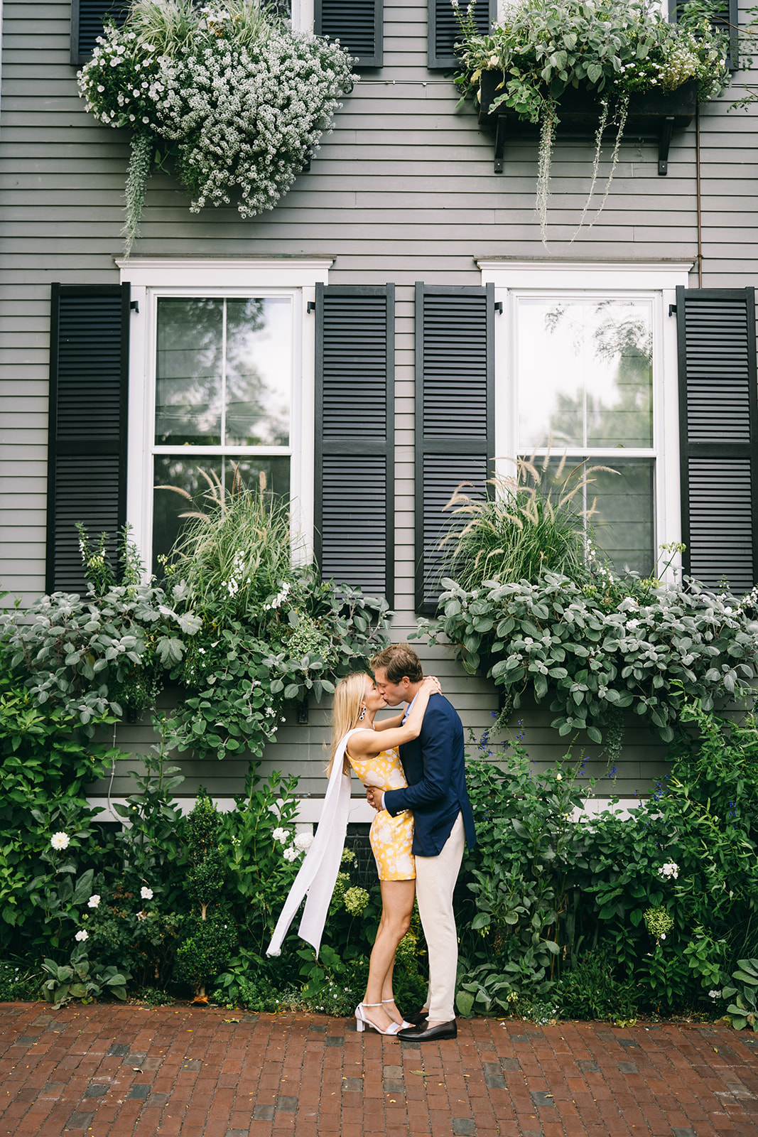 Couple kissing in front of church with thick foliage falling from the windows