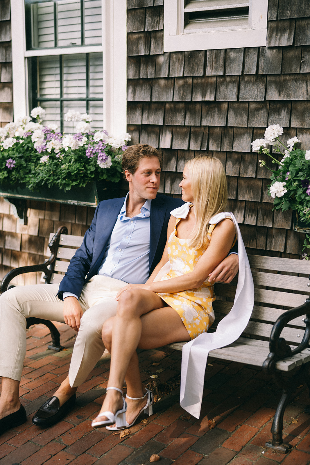 Man with arm around a woman sitting on a bench talking 