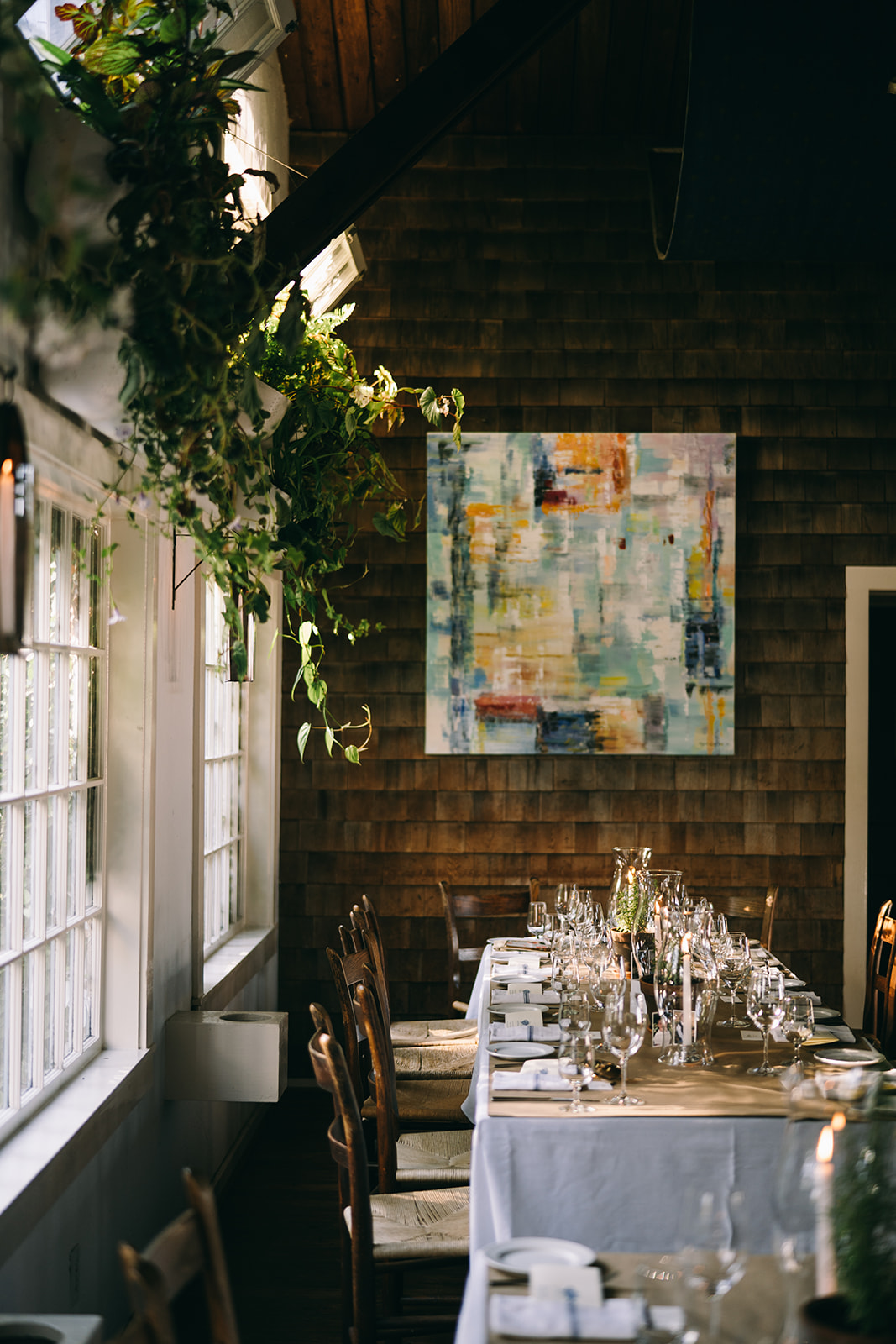 Table setting next to large open windows and plants inside 