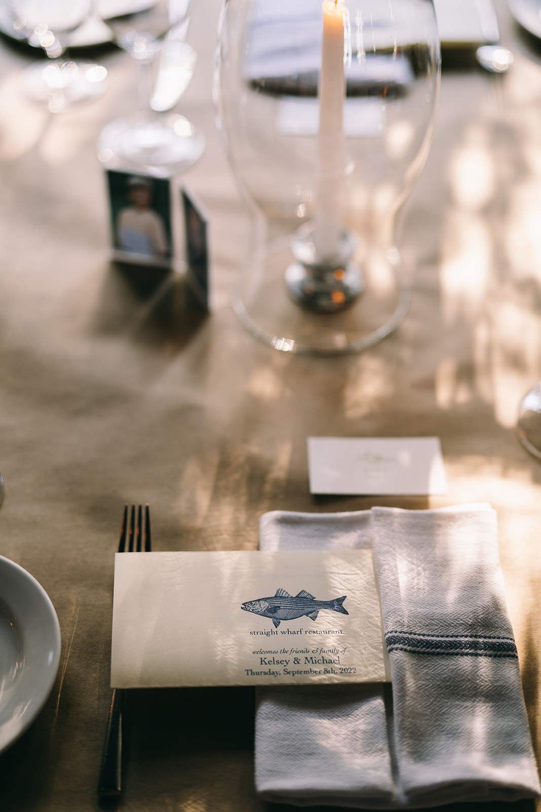 Welcome letter folded into white and blue napkin at table with a white candle encased in a cylinder