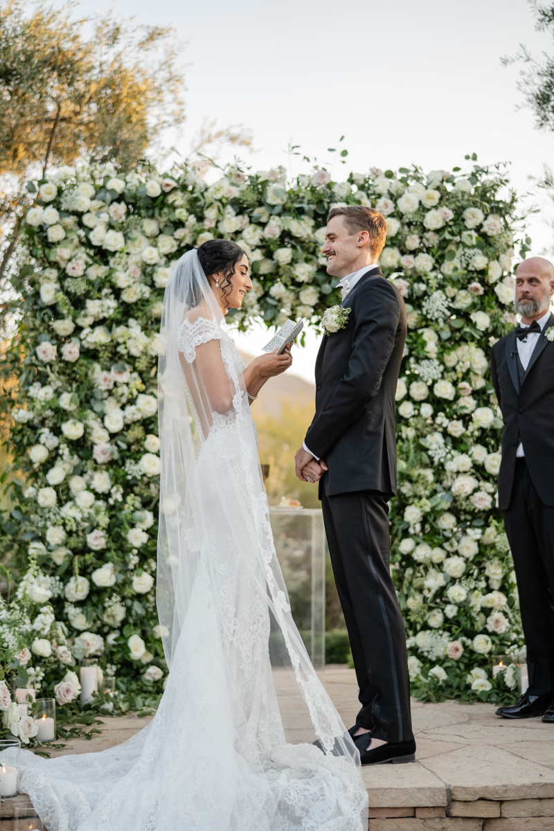 bride and groom at ceremony with flower wall