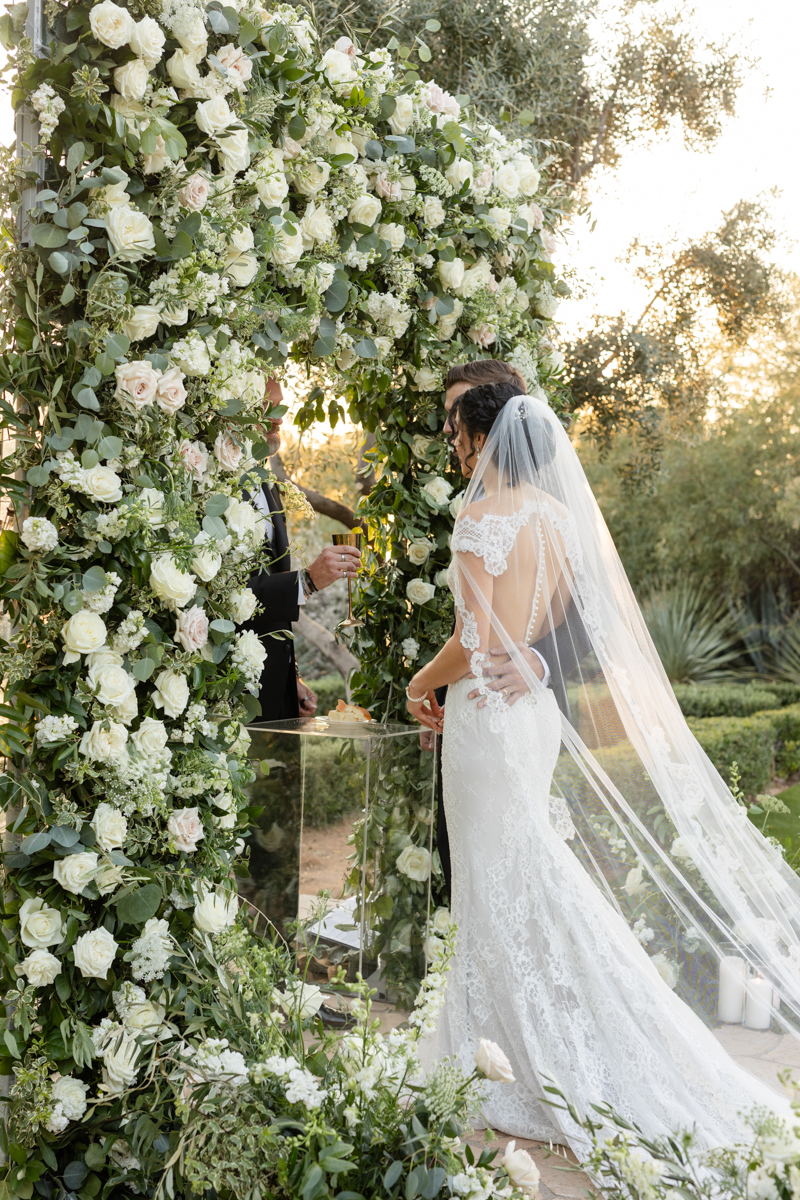 bride and groom at ceremony with flower wall