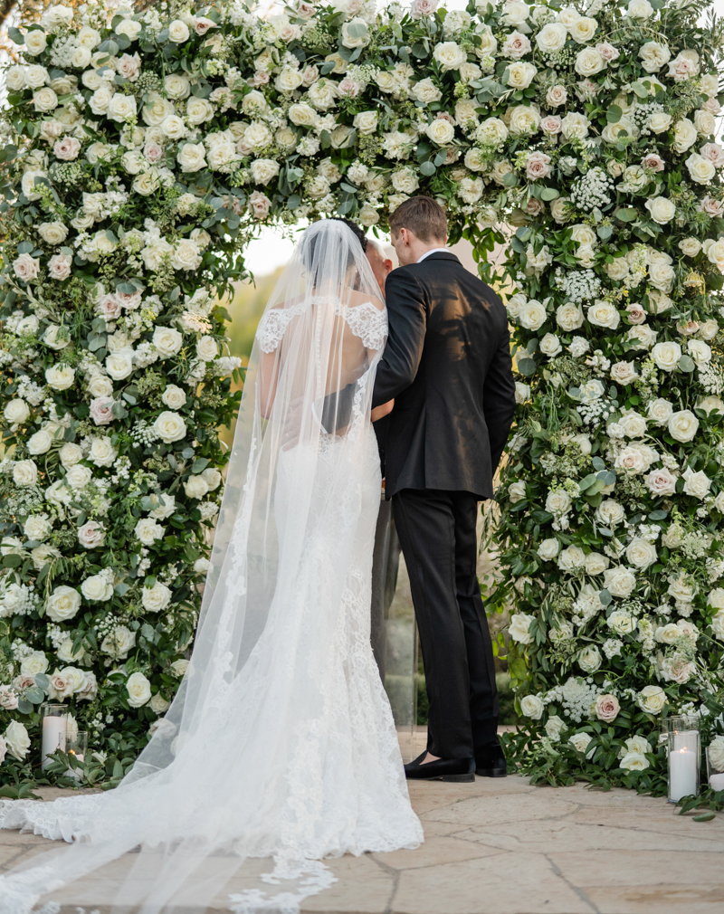 bride and groom at ceremony with flower wall