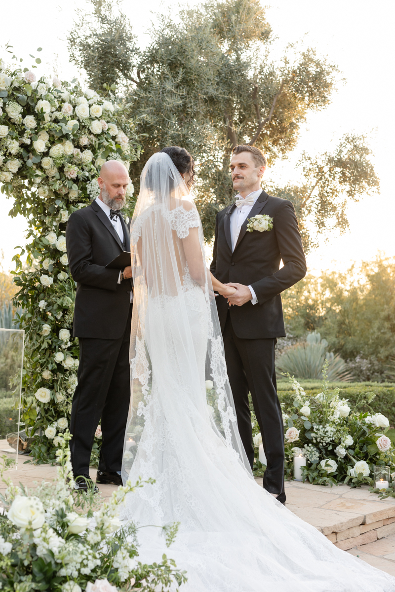 bride and groom at ceremony with flower wall