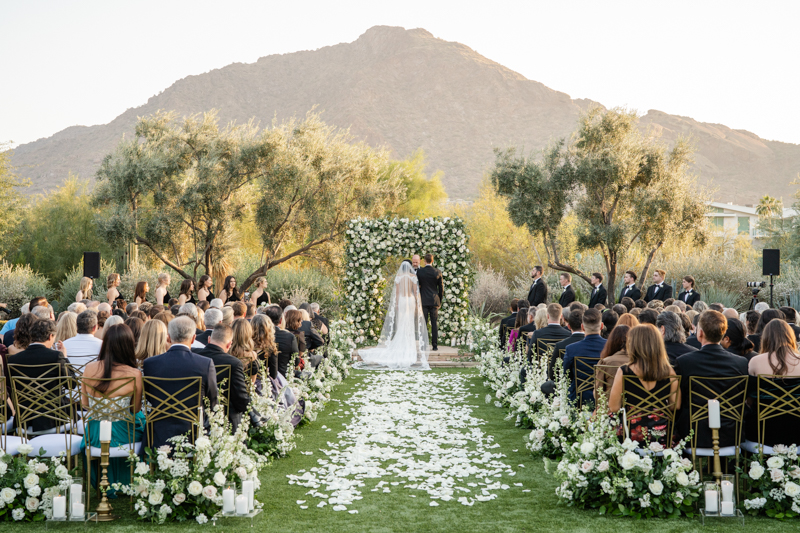 bride and groom at ceremony with flower wall camelback mountain