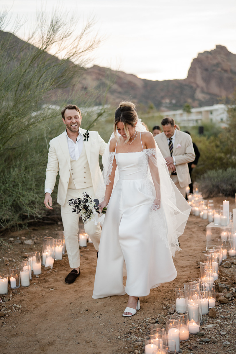 bride and groom walking down candle lit aisle